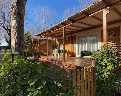 Sonnige terrasse eines Mobilheims aus Holz mit Gartenmöbeln und Begrünung im Feriendorf Club del Sole in Grado